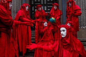 Foto på människor i röda kläder och vitmålade ansikten.